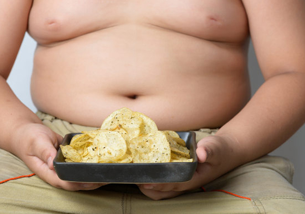Criança gorda segurando batata chips