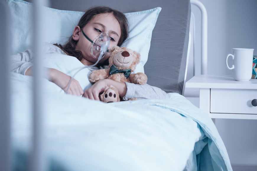Menina deitada usando um inalador; oxigenaÃ§Ã£o faz parte do tratamento do broncoespasmo.